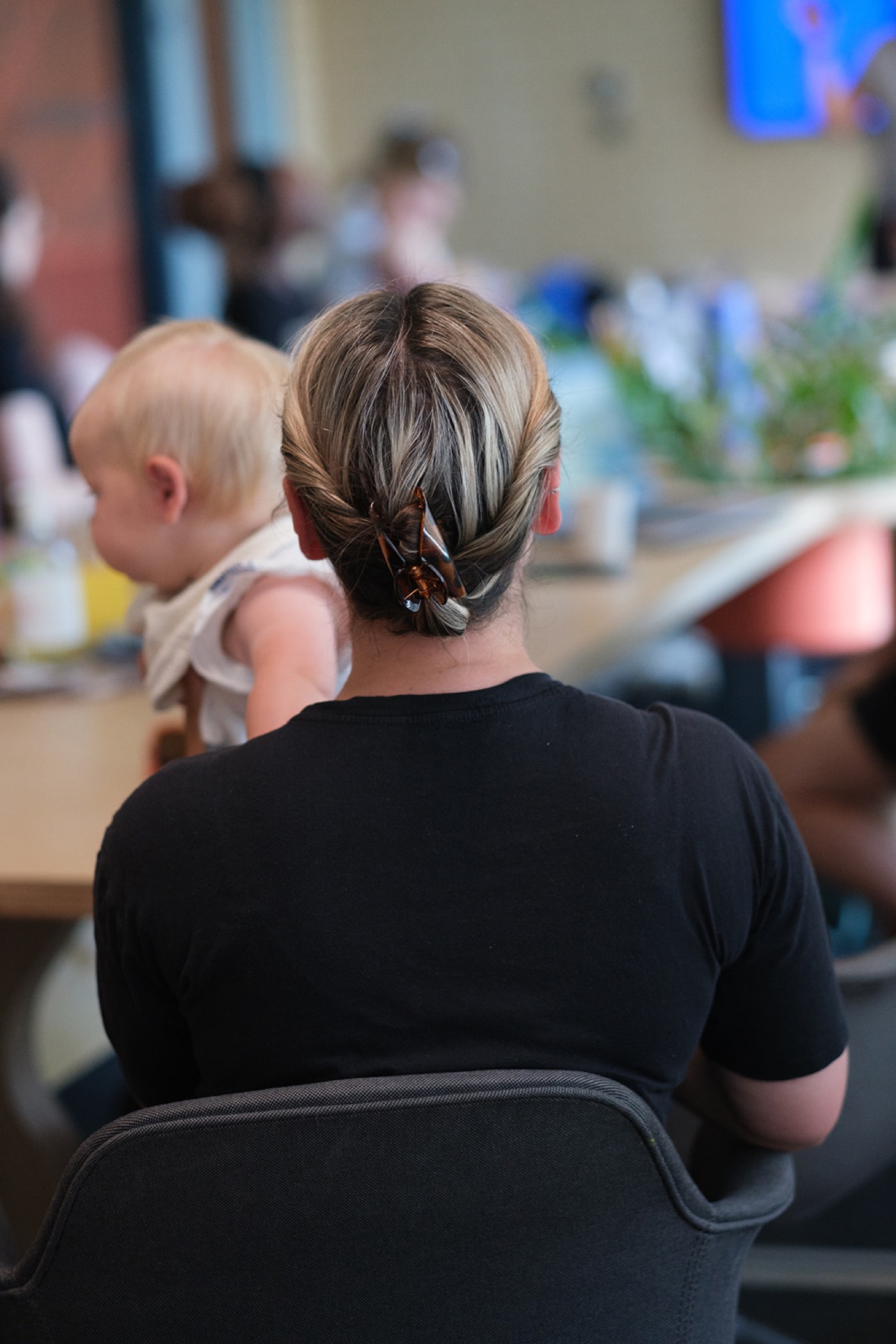 A mum from behind, hair clipped up, with her baby at the pilot
